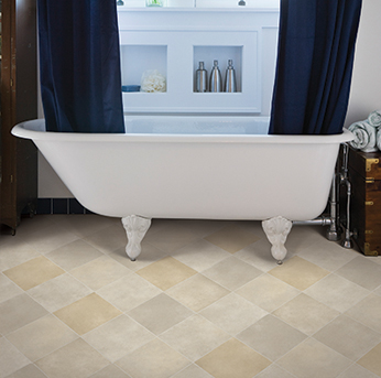 White clawfoot bathtub over beige diagonal tile flooring.