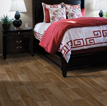 Bedroom with red bedding, dark furniture, and wood-look plank flooring.
