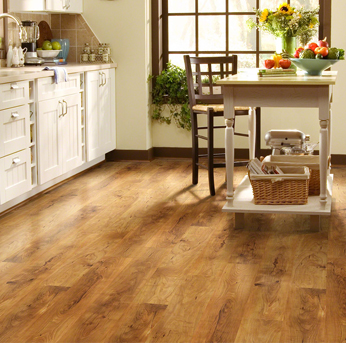 A kitchen with warm, medium-tone wood flooring, white cabinetry, and a small island.