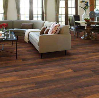 A living room featuring medium brown wood-look flooring and a light sectional sofa.
