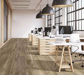 Open-plan office workspace featuring light wood-look vinyl flooring.