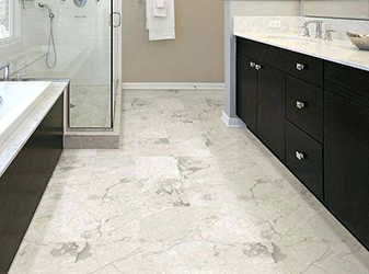 Light veined marble floor tile in a bathroom with dark cabinets.